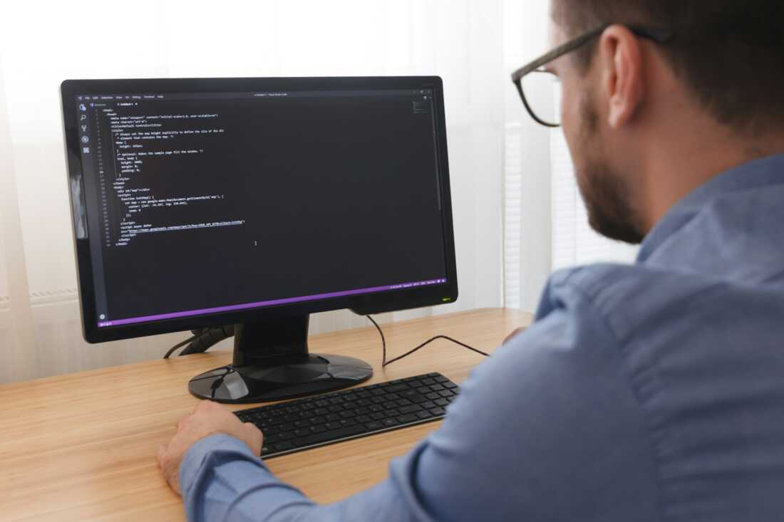 Programmer in Glsses Typing New Lines of HTML Code. Web Design Business and Web Development Concept